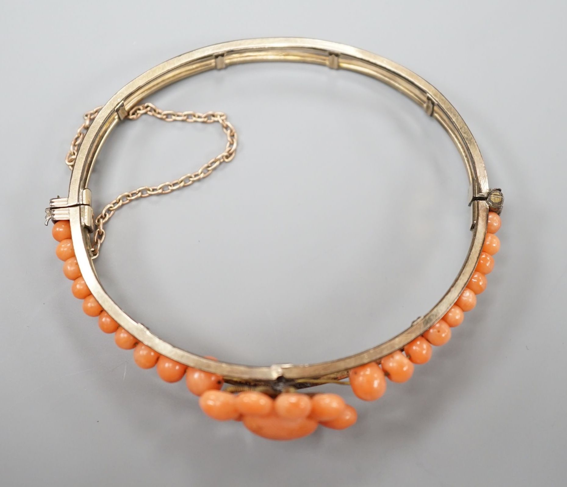 A gold plated and coral bead cluster set hinged bangle.